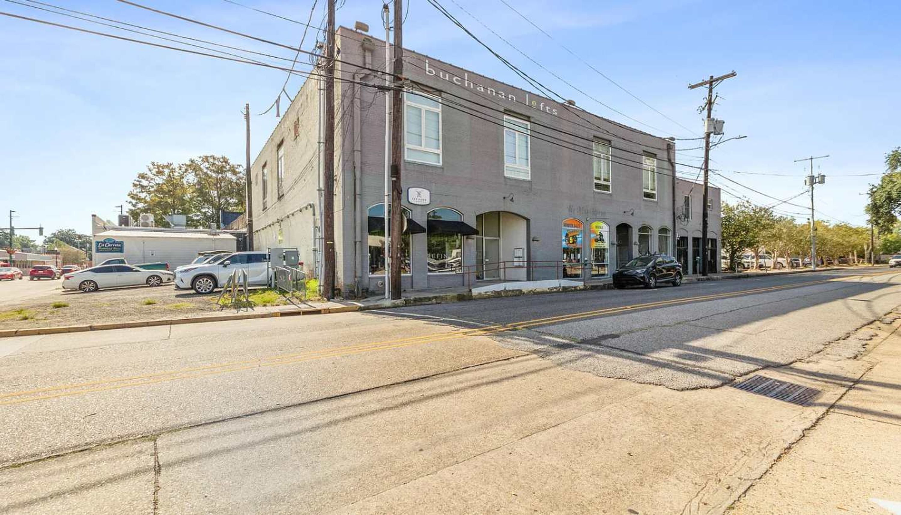 A two-story building with a sign reading "buchanan lofts" on the ground floor. There are parked cars on the street in front.