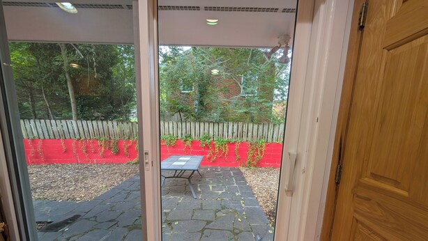Un patio con una mesa y sillas, un muro rojo y una cerca de madera.