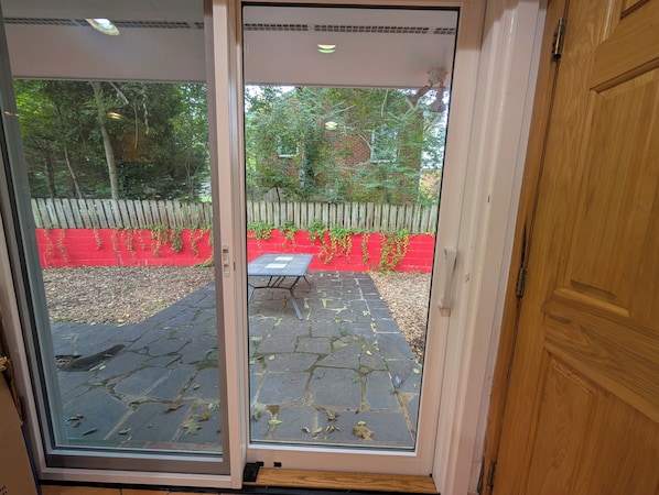 A patio with a table and chairs, a red wall, and a wooden fence.