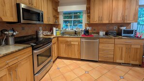 Una cocina moderna con gabinetes de madera, electrodomésticos de acero inoxidable y salpicadero de azulejos.
