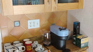 Una cocina con armarios de madera, una cafetera y varias tazas en la encimera.