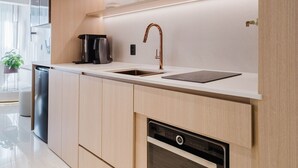 A modern kitchen with wooden cabinets, a built-in oven, a coffee maker, and a sink. - Viana Dream Modern Studio in Pinheiros (São Paulo)