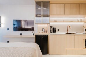 A modern kitchen with wooden cabinets, a black dishwasher, and a countertop with a sink and coffee maker. - Viana Dream Modern Studio in Pinheiros (São Paulo)