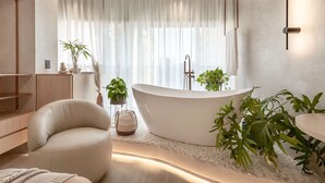 Een moderne badkamer met een vrijstaand bad, een rond zitgedeelte en diverse planten.