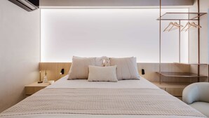 A modern bedroom with a large bed, a bedside table with a lamp, and a wall-mounted drying rack. - Viana Dream Modern Studio in Pinheiros (São Paulo)