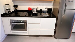 A modern kitchen with wooden cabinets, a built-in oven, a stainless steel refrigerator, and a black countertop. - Do Pinheiros I Stylish Studio in Sao Paulo (São Paulo)