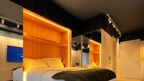 A modern bedroom with a large bed, built-in wooden shelving, a flat-screen TV, and a mirror. - Do Pinheiros I Stylish Studio in Sao Paulo (São Paulo)