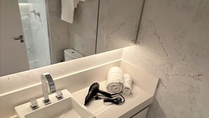 A modern bathroom with a white sink, a hairdryer, and neatly folded towels on the vanity. - Do Pinheiros I Stylish Studio in Sao Paulo (São Paulo)