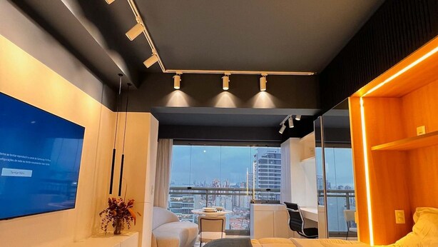 A modern hotel room with a large bed, a desk, a chair, and a TV on the wall. - Do Pinheiros I Stylish Studio in Sao Paulo (São Paulo)