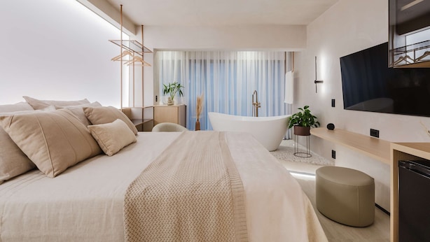 A modern bedroom with a large bed, a bedside table, a TV, and a bathtub. - Viana Home Design Studio in Pinheiros (São Paulo)