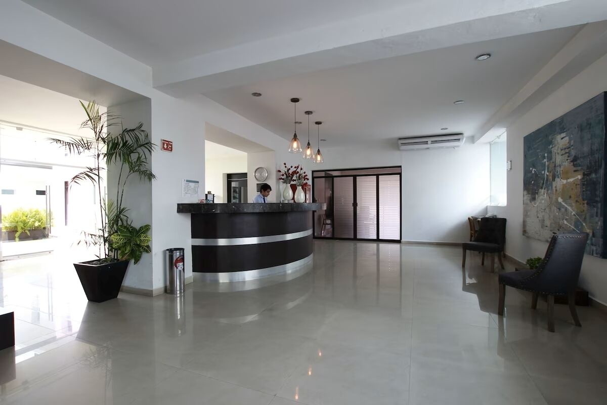 A spacious lobby with a reception desk, potted plants, and a large abstract painting on the wall.