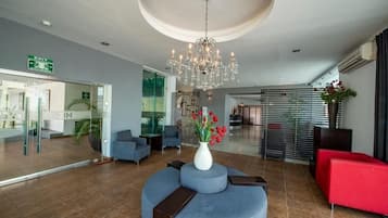 Um lobby moderno com um candelabro, áreas de estar e um balcão de recepção.