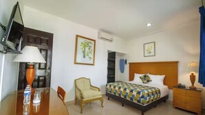 Une chambre d’hôtel équipée d’un lit, d’une chaise, d’un bureau avec une lampe, d’une télévision et d’un appareil de climatisation.