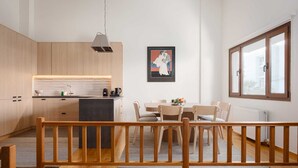A modern kitchen with wooden cabinets, a dining area with a table and chairs, and a large window providing natural light.