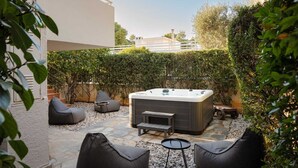 An outdoor patio area with a hot tub, seating, and a stone pathway.