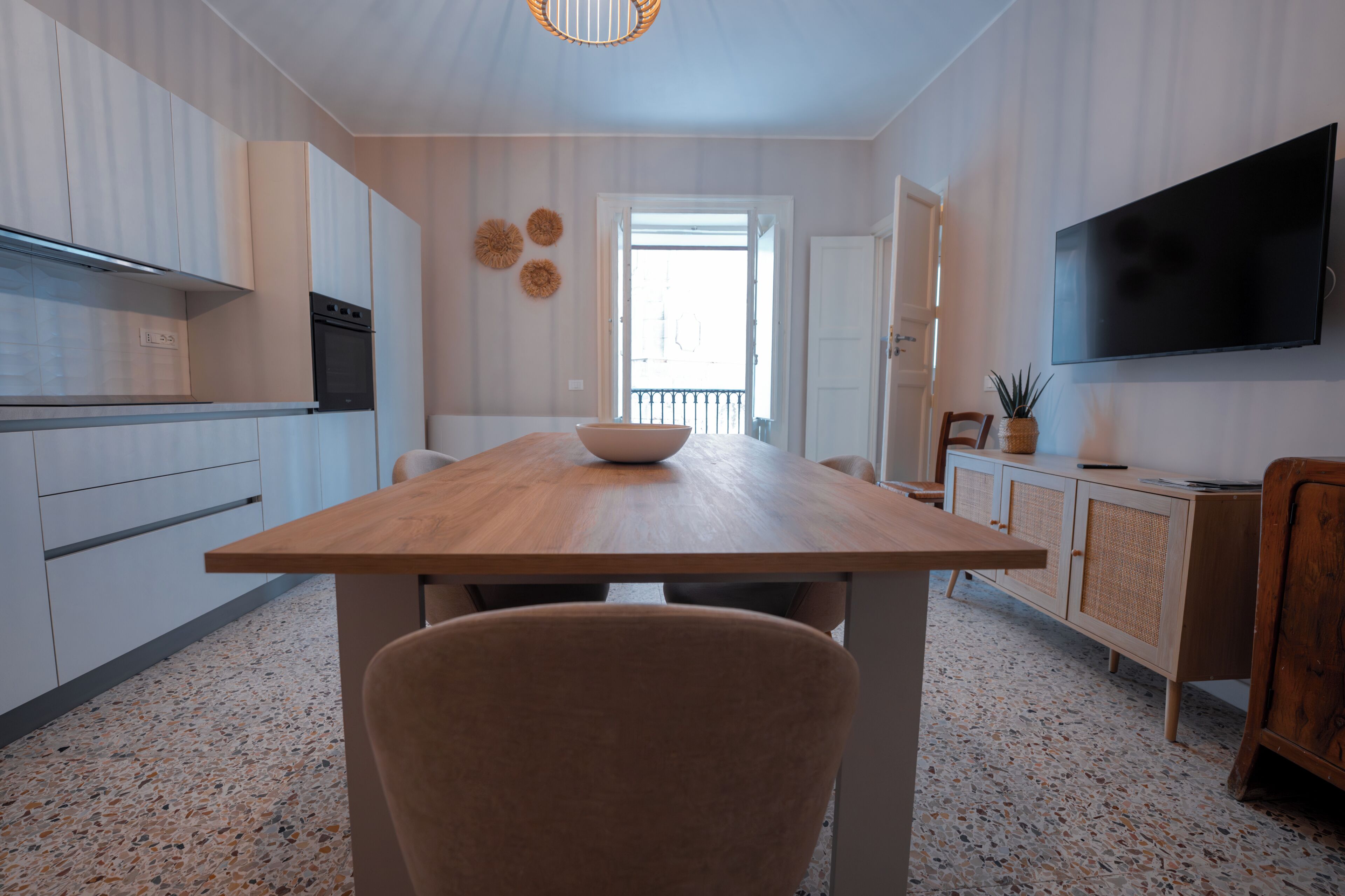 Une cuisine moderne avec une table en bois, un saladier et un téléviseur.
