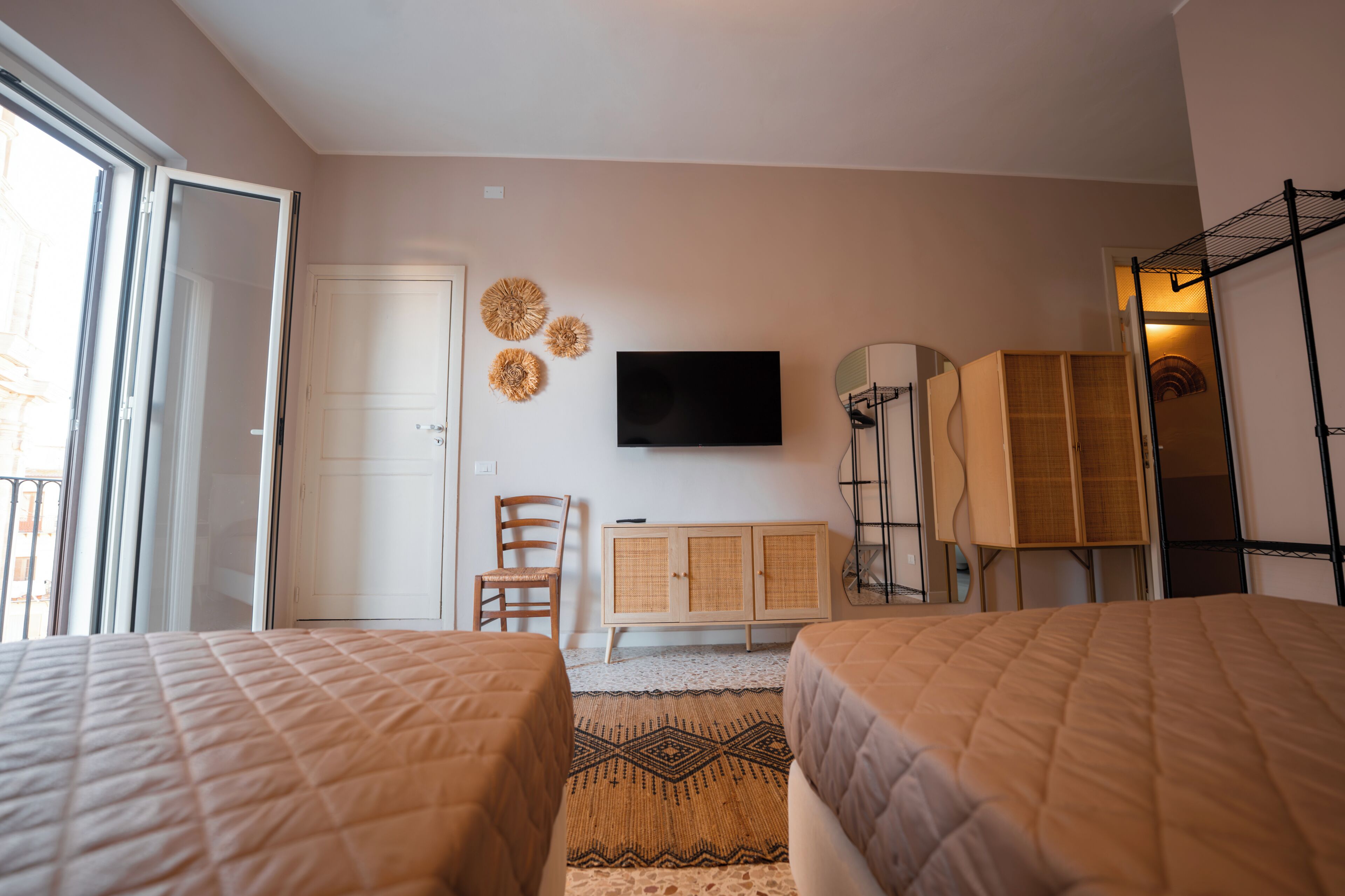 A hotel room with two beds, a TV, a cabinet, and a wardrobe.
