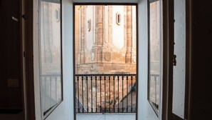 A view through a door with a metal gate leading to an outdoor area with a stone building and a small plant. - Casa Manbrù by Studio Vita (Siculiana)