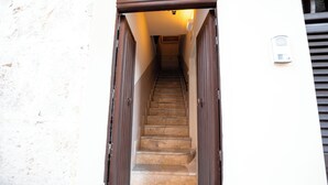A staircase leading to a door, with a wall-mounted intercom on the right. - Casa Manbrù by Studio Vita (Siculiana)