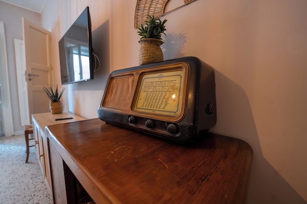 A wooden table with a vintage radio, a television mounted on the wall, and a potted plant. - Casa Manbrù by Studio Vita (Siculiana)