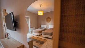 A bedroom with two beds, a desk, and a television mounted on the wall. - Casa Manbrù by Studio Vita (Siculiana)