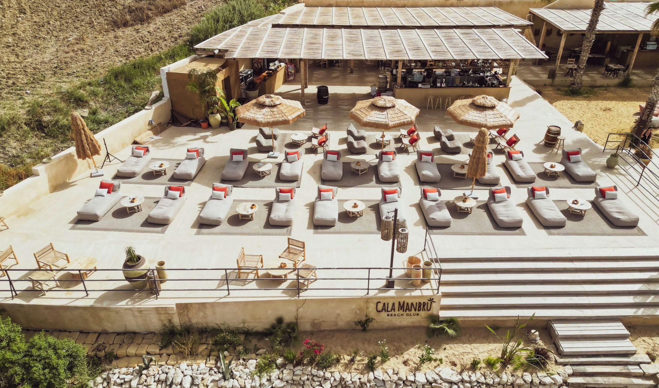Um clube de praia com espreguiçadeiras e guarda-sóis, acesso livre e estacionamento.