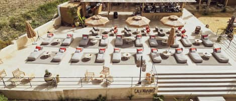 A beach club with sun loungers and umbrellas, free access, and parking.