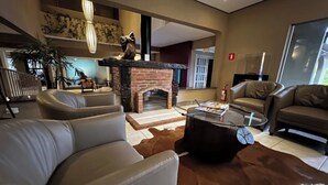 Una sala de estar moderna con sofás de cuero, una mesa de centro de vidrio, una chimenea y un ventanal grande.