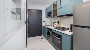 Une cuisine moderne avec des meubles de couleur turquoise, un réfrigérateur en acier inoxydable, une cuisinière à gaz et un four à micro-ondes.