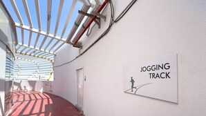 Un couloir avec un panneau indiquant une piste de jogging, une porte et un sol rouge.