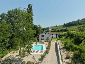 A villa with a swimming pool, surrounded by greenery and hills.