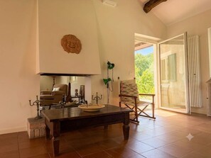 A living room with a dark wooden table, a chair, a candelabra, and a window with a view of greenery.
