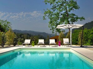 A swimming pool with lounge chairs, a wooden cabin, and a mountainous backdrop. - Casale Bera, hills view, private pool and garden (Cossano Belbo)