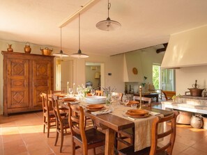 A dining area with a wooden table set for six, surrounded by chairs. There is a wooden cabinet with decorative items on top.