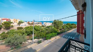 A balcony with a view of a coastal town, a clear sky, and a sea in the distance. - Luz del Faro, apartment in historic townhouse with sea view - by OYOOSTAYS (La Vila Joiosa)