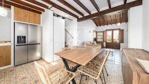 A spacious kitchen with a wooden table and wicker chairs, a built-in fridge, and a view of the outside through a large window. - Luz del Faro, apartment in historic townhouse with sea view - by OYOOSTAYS (La Vila Joiosa)