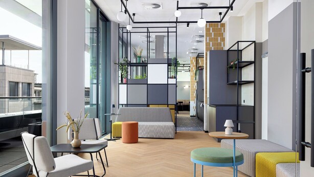 A modern interior with a sofa, chairs, a round table, and a bookshelf.