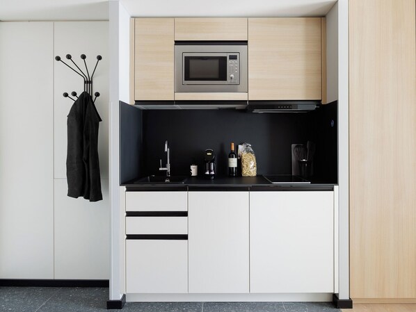 Una cocina moderna con microondas integrado, un lavamanos y una cafetera.