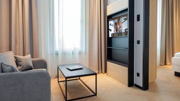 Ein modernes Wohnzimmer mit einem grauen Sofa, einem Couchtisch und einem an der Wand befestigten Fernseher.