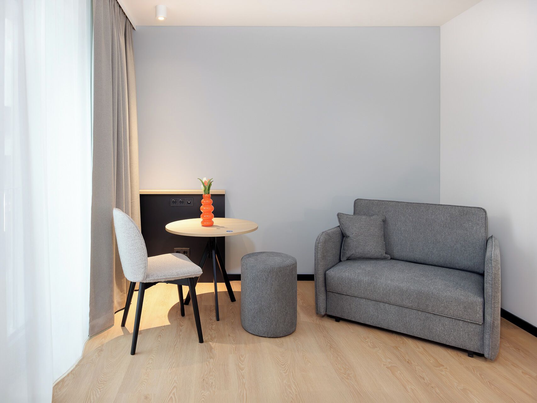 Una sala de estar moderna con un sofá gris, una mesa redonda y una silla.