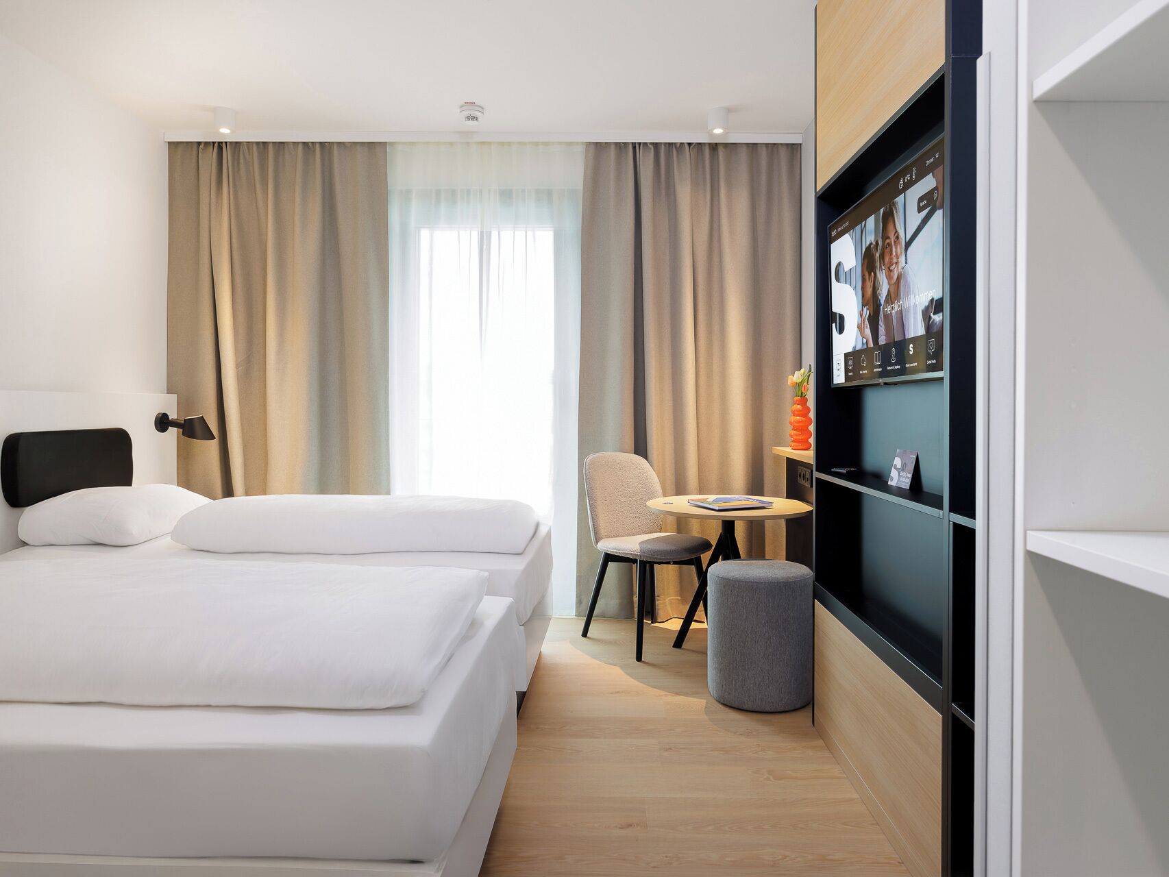 A modern hotel room with a large bed, a desk, and a television.