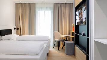 A modern hotel room with a large bed, a desk, and a television.