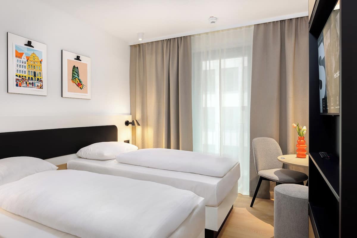 Una habitación de hotel con dos camas, un escritorio, una silla y un televisor.