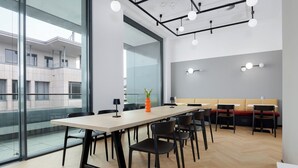 A modern conference room with a large table, chairs, and a glass wall offering a view of the building's exterior.