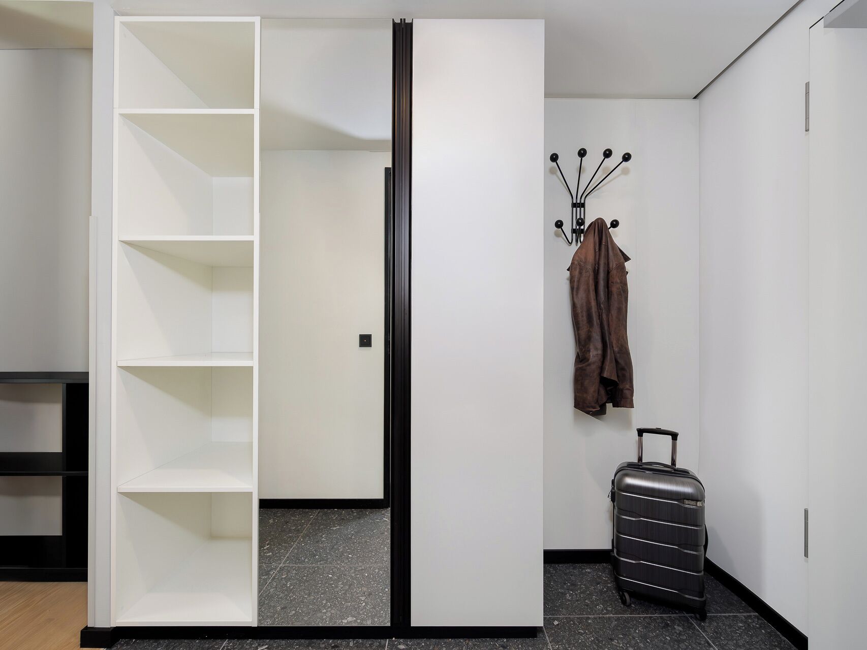 A room with a wardrobe, a coat rack, and a suitcase.