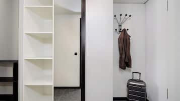 A room with a wardrobe, a coat rack, and a suitcase.
