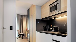 A modern kitchen with a microwave, coffee machine, and a sink. There is a dining area with a table and chairs visible in the background.