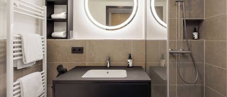 A modern bathroom with a black sink, two mirrors, a towel rack, and a shower.
