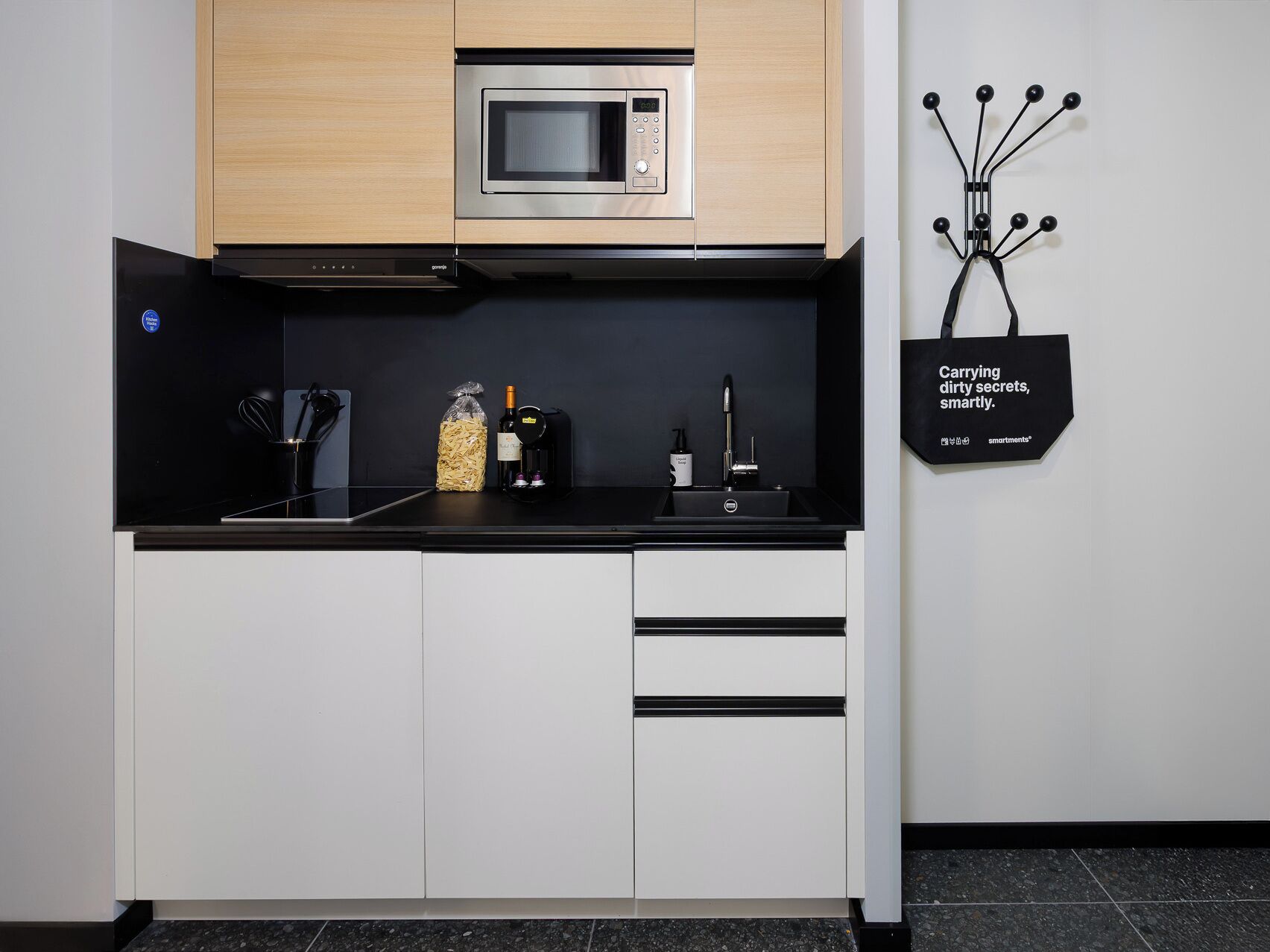 Una cocina moderna con un microondas, un fregadero y una botella de vino.