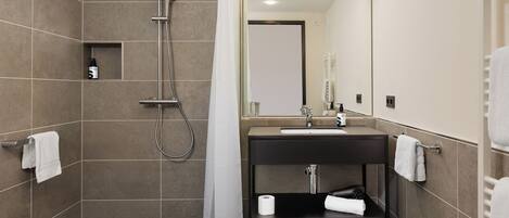 A modern bathroom with a shower, sink, and mirror.